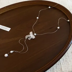 Detail showing the sparkling rhinestone bow and pearl accents on the Y-shaped necklace