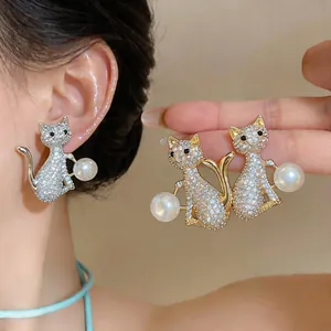 Détail de boucles d'oreilles chat avec zircons étincelants et perles
