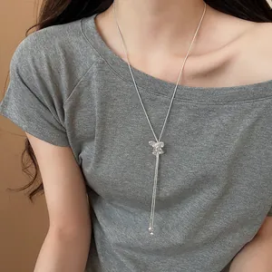 Detailed view of silver Y-shaped sweater chain with sparkling bow charm and pearls