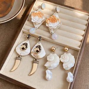 Exquisite detail view of seaside style resin shell and conch earrings with baroque pearls