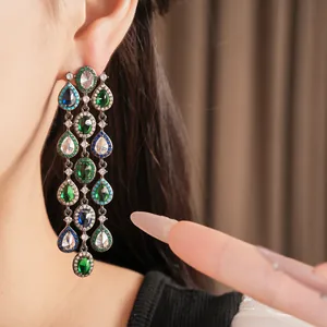Nahaufnahme von eleganten Vintage-Quastenohrringen mit grünen und blauen Zirkonsteinen.