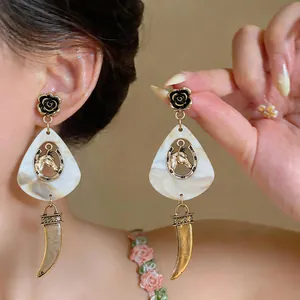 Close-up of vintage gold horse head earrings with black rose and marbled teardrop