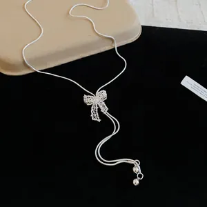 Close-up of a sparkling silver bow knot Y-shape lariat necklace detail on black velvet