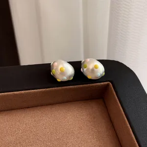 Primo piano di orecchini a perno ovali in argento opaco con pois colorati a goccia
