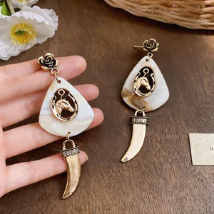 Elegant close-up view of vintage dangle earrings with rose studs and marble horse charms