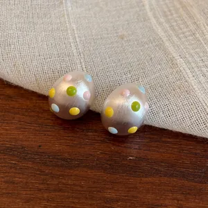 Dettaglio macro della finitura opaca e dei pois colorati degli orecchini ovali