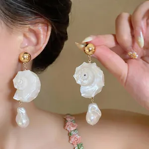 Close-up of elegant shell and conch drop earrings with baroque pearls for vacation.