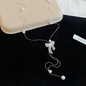 Close-up of rhinestone bow pendant and pearl details on silver-tone Y-shaped chain