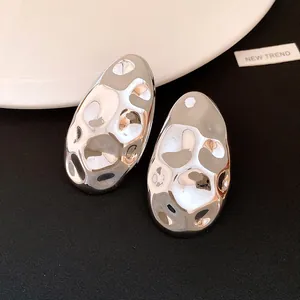 Detailed macro view of silver oval earrings with liquid metal hammered texture finish