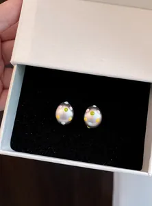 Dettaglio di orecchini a lobo ovali opachi con pois colorati in una confezione regalo