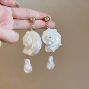 Detailed view of handmade shell conch dangle earrings featuring elegant baroque pearl drops