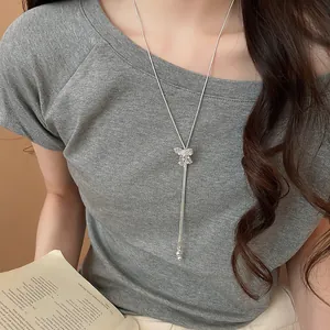 Detailed shot of a silver Y-shaped necklace with a sparkling bow pendant on a model