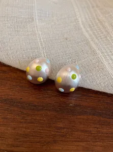 Dettaglio ravvicinato di orecchini a perno ovali in argento opaco con pois colorati
