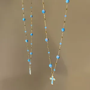Detailed view of a vintage beaded cross necklace with blue stone beads and gold chain