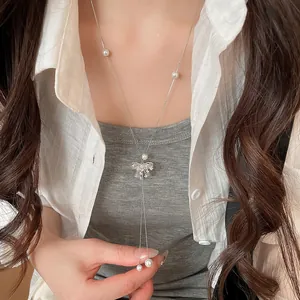 Macro detail of a sparkling bow knot Y-shaped long pearl necklace worn on a model