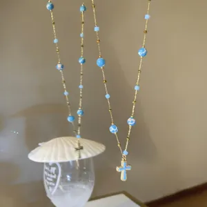 Detailed macro view of a vintage style blue beaded necklace with a gold cross pendant