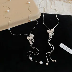 Detailed view of silver bow pendant necklace with pearls on a black velvet background