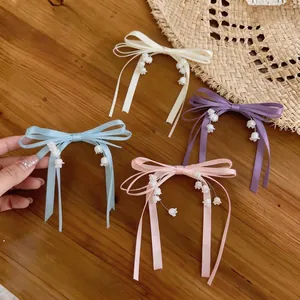 Eleganti fermagli per capelli con fiocchi di nastro e fiori di mughetto su un tavolo