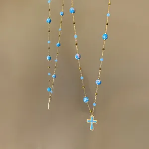 Detailed view of a vintage gold-toned necklace with blue beaded stones and a cross pendant