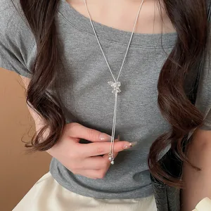 Close-up of elegant silver Y-shaped necklace featuring a sparkling rhinestone bow pendant.