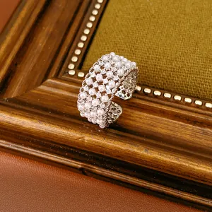 Macro detail of silver-finish multi-layer ring with rows of white pearls and zircons
