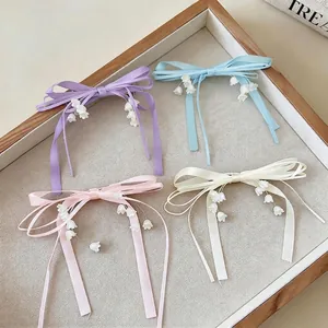 Eleganti fermagli per capelli con fiocchi in nastro e ciondoli a fiore di mughetto.