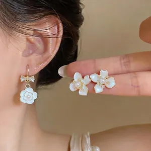 Detail shot of French luxury camellia earrings with pearls and zircons on model
