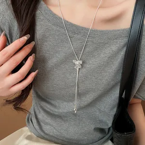 Detailed view of a sparkling butterfly Y-necklace worn over a grey sweater texture.