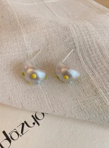 Primo piano di orecchini a lobo a forma di C in argento opaco con pois colorati