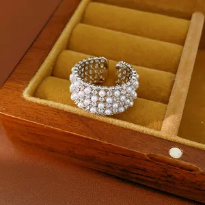 Macro detail of a silver-toned open ring featuring layers of white pearls and zirconia stones