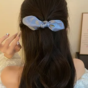 Vue détaillée d'une élégante pince à cheveux banane en satin bleu sur cheveux longs