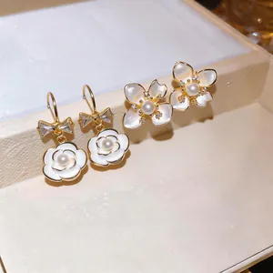 Macro view of French luxury camellia pearl earrings with gold-plated zircon accents