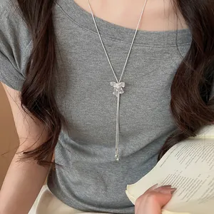Detailed view of a sparkling bow pendant on a silver-tone Y-shaped long necklace.