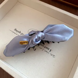 Détail d'une pince à cheveux banane en satin bleu clair avec nœud dans sa boîte vintage