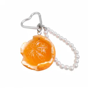 Realistic peeled orange keychain with pearl beads and heart-shaped clip on white background