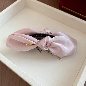 Gros plan d'une pince à cheveux banane en satin rose élégante avec détail doré