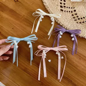Dettaglio di quattro fermagli per capelli a fiocco colorato con ciondoli a mughetto