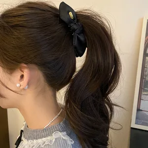 Vue détaillée d'une pince à cheveux banane en satin noir noué sur une queue de cheval