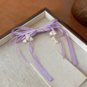 Dettaglio di un fermaglio per capelli con fiocco viola e nappe di mughetto eleganti