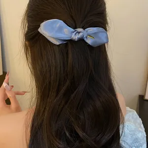 Vue détaillée d'une élégante pince à cheveux en satin bleu noué sur de longs cheveux