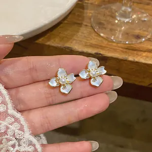 Close-up of elegant camellia earrings with pearl and zircon details in gold finish