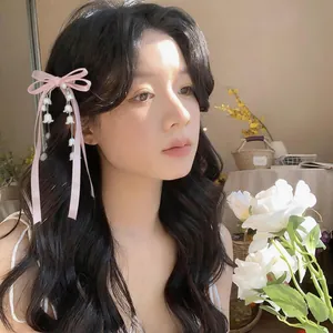 Elegante fermaglio per capelli rosa con fiocco e nappe di mughetto su modella