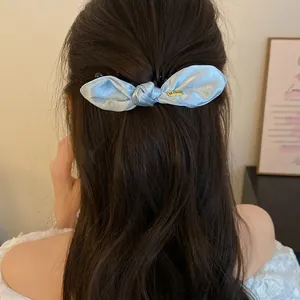 Vue arrière d'une pince banane à nœud en satin bleu clair sur cheveux bruns
