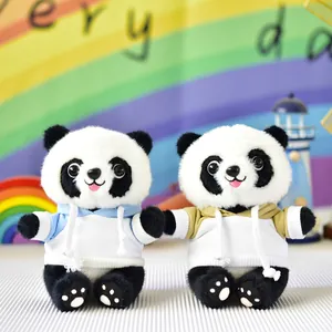 Two cute panda plush toys wearing blue and yellow hoodies in a cozy room
