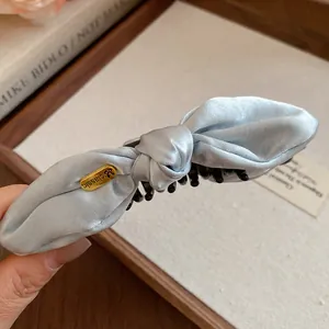 Gros plan d'une élégante pince à cheveux en satin bleu clair avec texture lisse et nœud