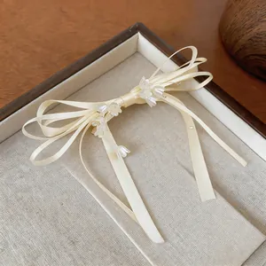 Dettaglio ravvicinato di un'elegante clip per capelli a fiocco crema con fiori di perla