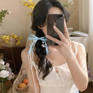 Dettaglio di un fermaglio per capelli in nastro blu con fiori di mughetto