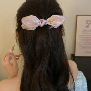 Gros plan élégant d'une pince à cheveux nœud en satin rose sur longs cheveux ondulés