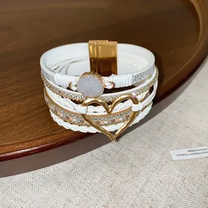 Detailed view of bohemian white leather braided bracelet with heart charm and magnetic clasp.
