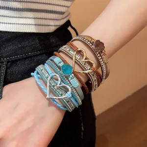 Close-up of bohemian multilayer leather bracelet with sparkling rhinestones and heart charm.